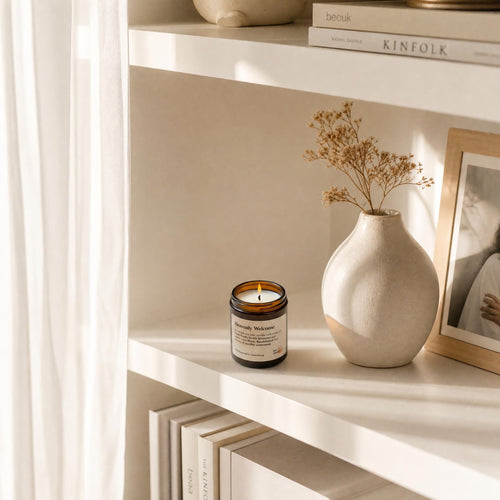 „Heavenly Welcome" Sojakerze auf hellem Bücherregal, weißes Interieur, florale Duftnoten – sanfte Eleganz für Zuhause