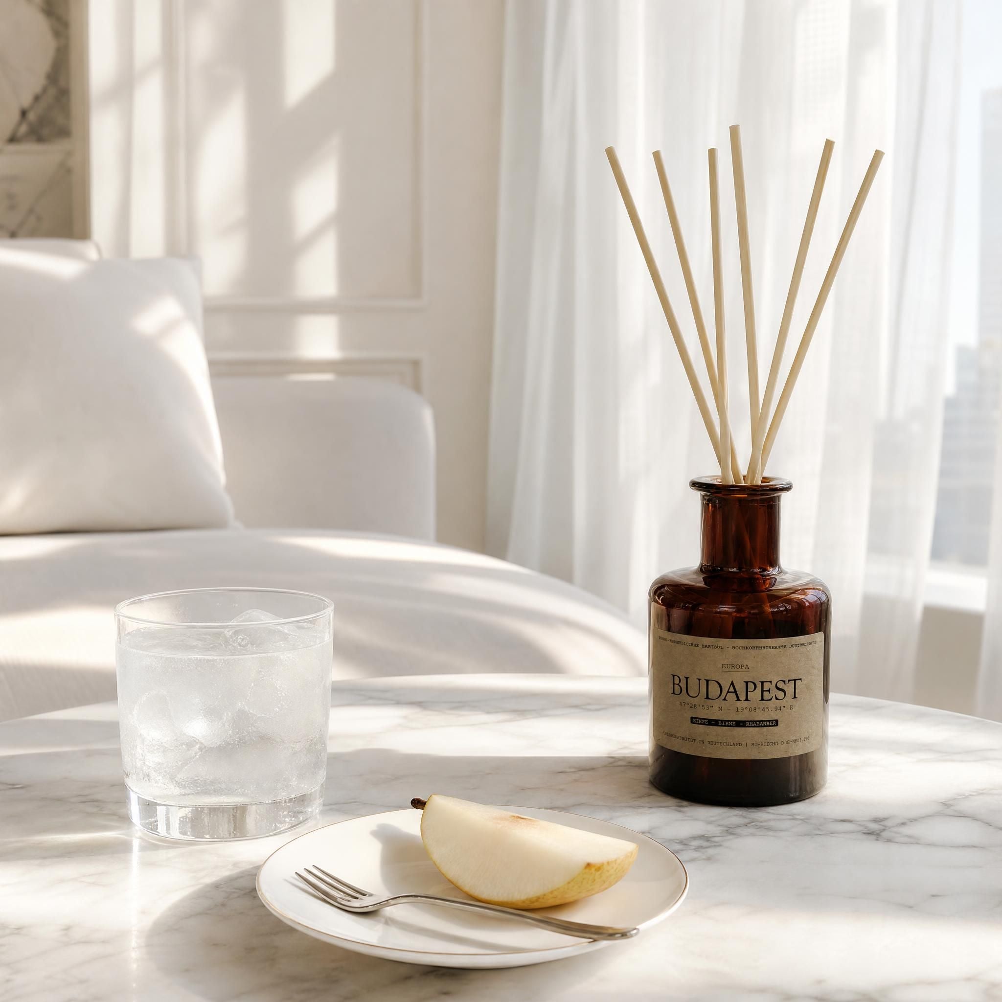Reed Diffuser „Budapest" im Bernsteinglas auf Marmortisch – Duft nach Quitte, Birne und Rhabarber, elegantes weißes Interieur