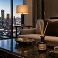 Reed Diffuser „Las Vegas" im Bernsteinglas auf dunklem Marmortisch – Skyline-Blick bei Nacht, modernes Penthouse-Ambiente